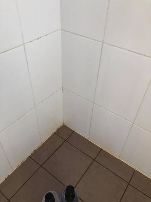 Shower corner with mould and stained grout before cleaning