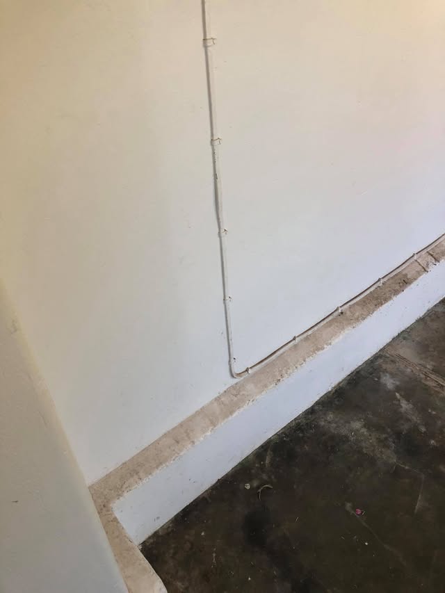 Wall and skirting board grimy with dust and cobwebs before cleaning